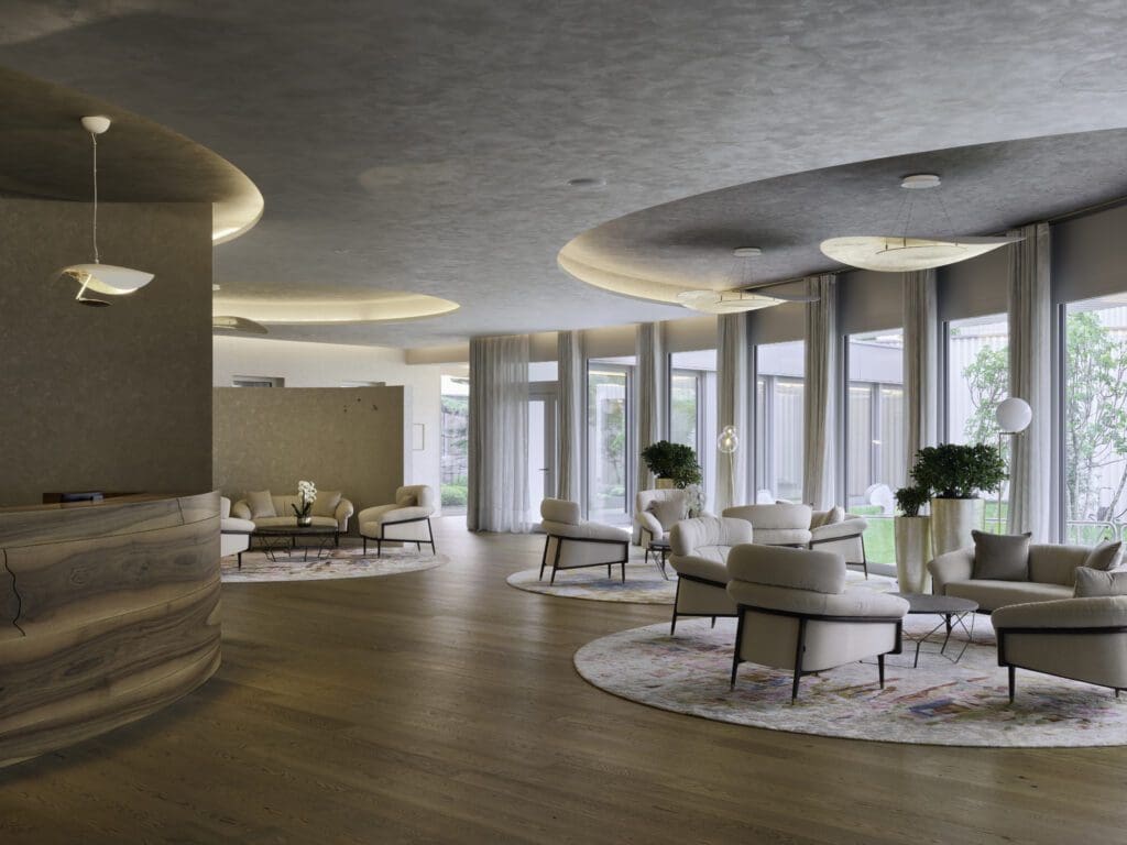 Modern lounge area with curved ceiling lights, neutral-coloured armchairs, round rugs, large windows, potted plants, and a stone reception desk on wooden flooring.