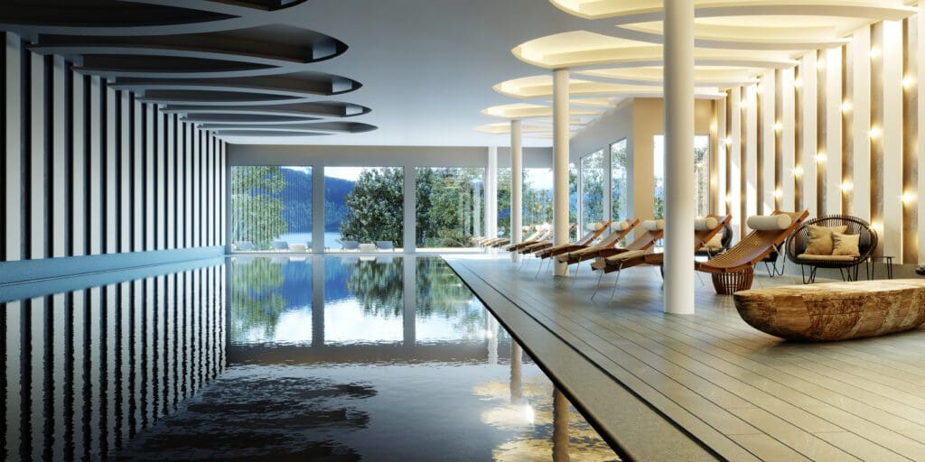 Modern indoor swimming pool with lounge chairs, large windows showing trees and a lake, wooden accents, and unique ceiling lights.